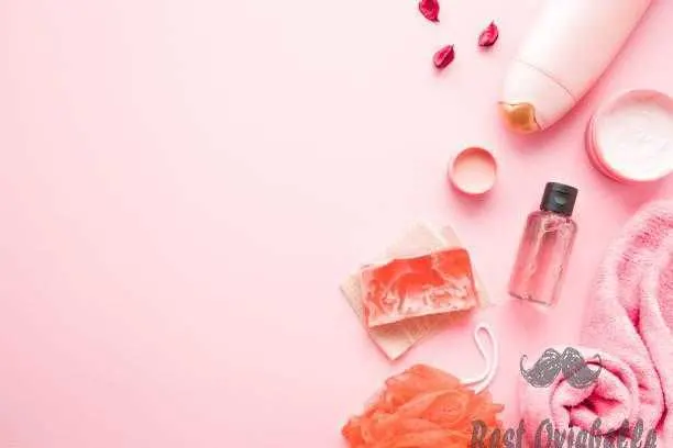 Cream jars shower bottle essential oil towel orange wisp and soap on pastel pink table. Relax products for body washing.