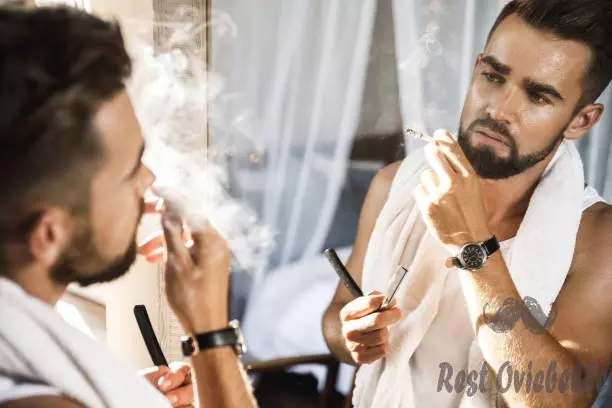 man looking in the mirror smoking a cigarette and shaving his beard with a straight razor - straight razor blades s and