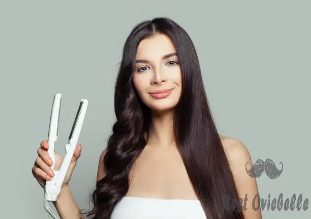 happy woman with straight hair and curly hair using hair straightener. cute girl straightening healthy brunette